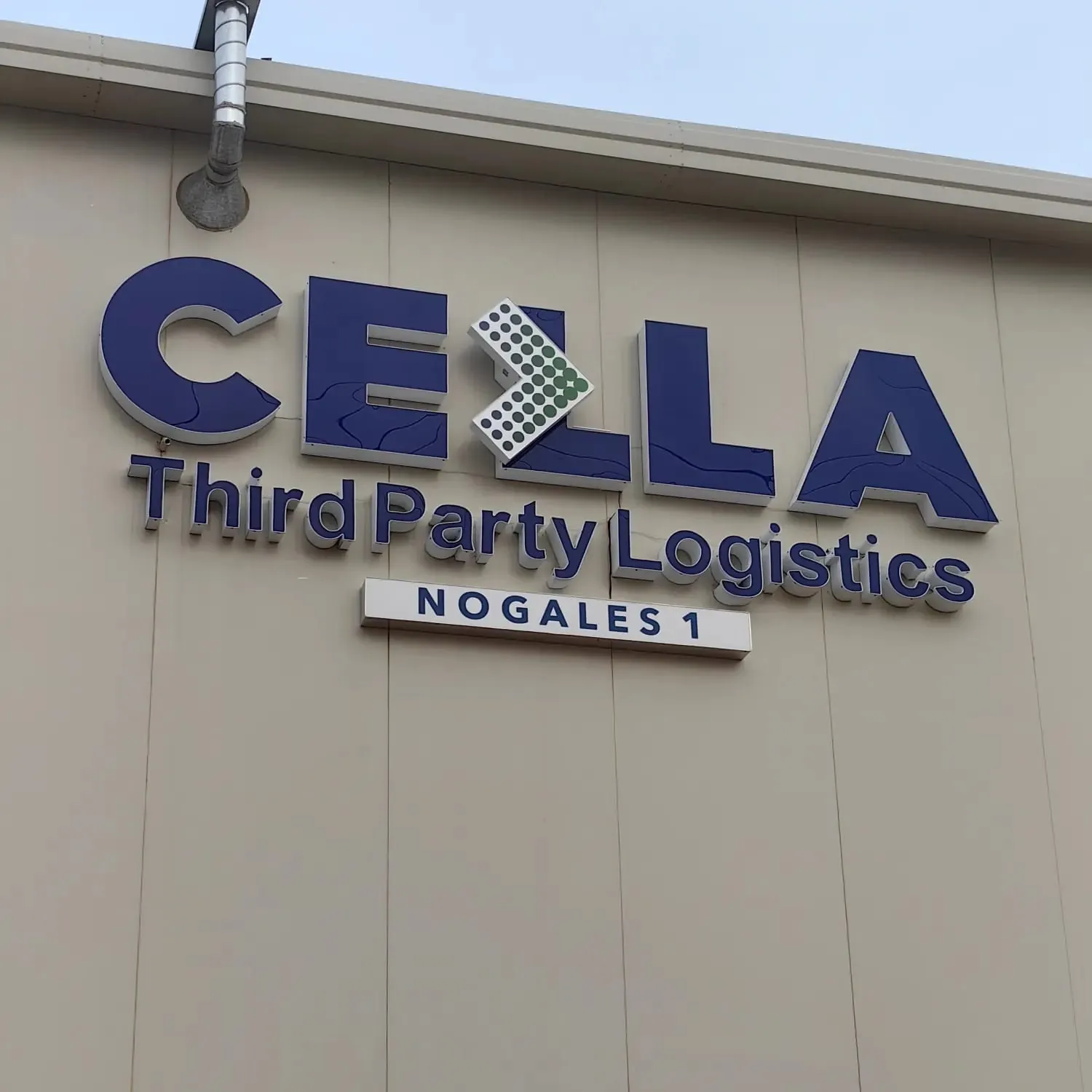 Letras de canal azules de CELLA Third Party Logistics en la fachada de una nave industrial