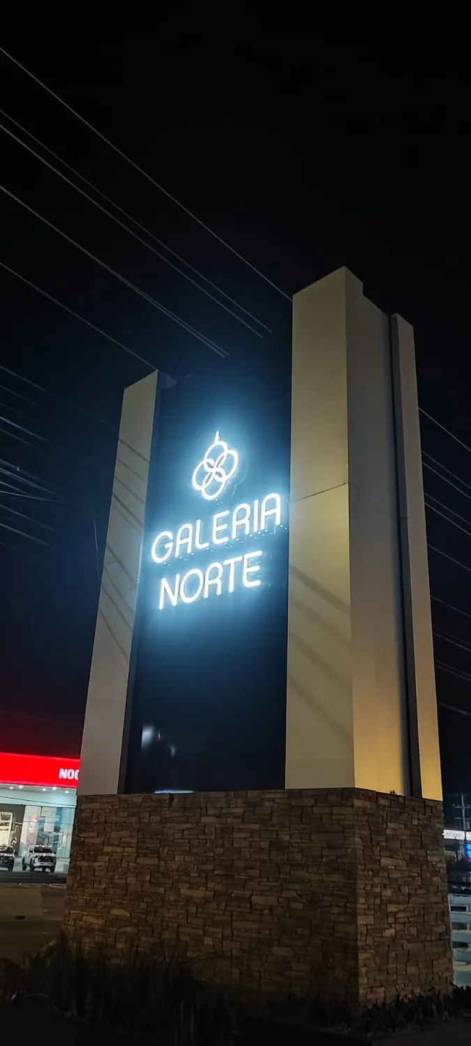 Pilono de la plaza Galería Norte de noche con el logotipo y las letras iluminadas en blanco