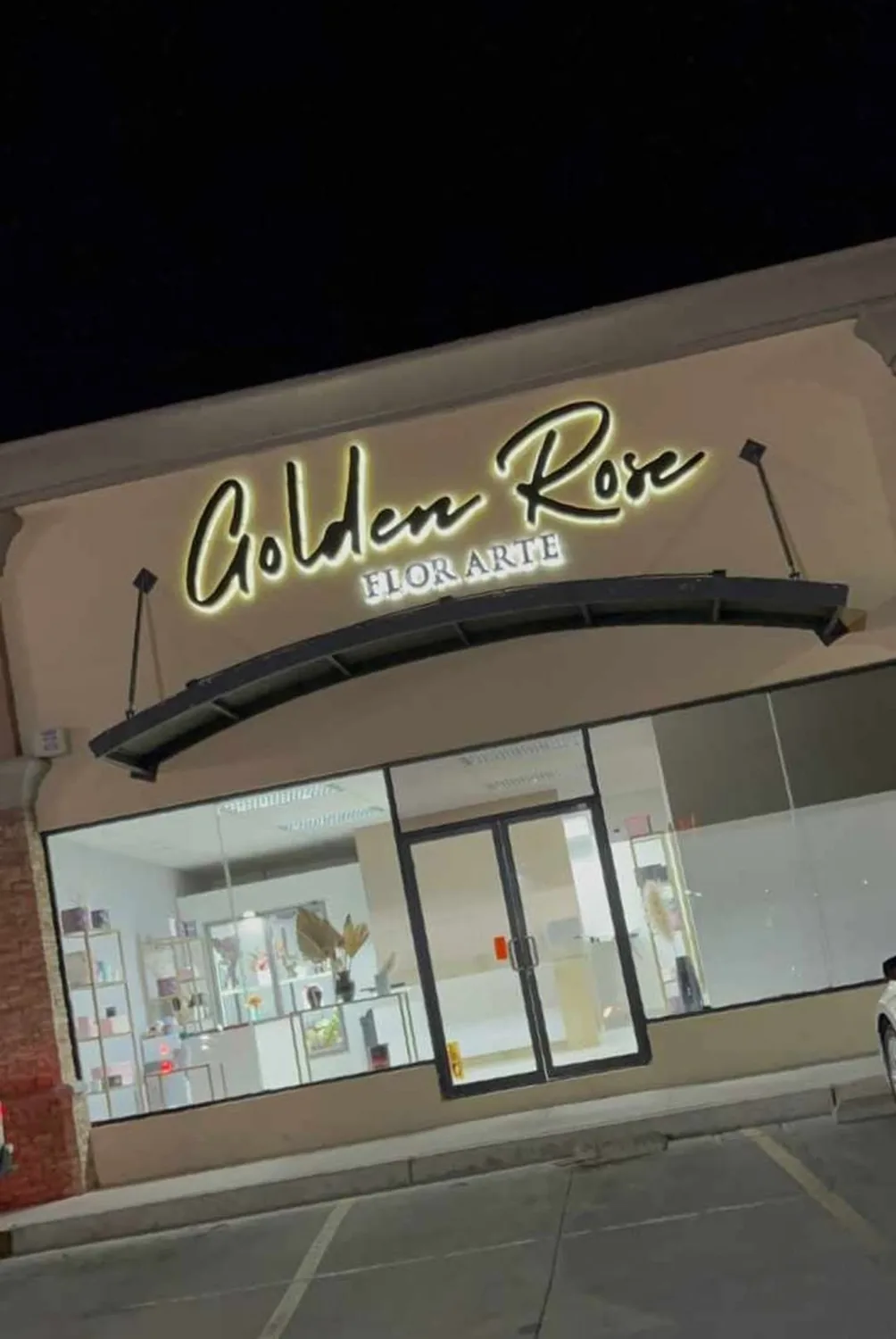 Fachada de Golden Rose Flor Arte de noche con las letras iluminadas por detrás