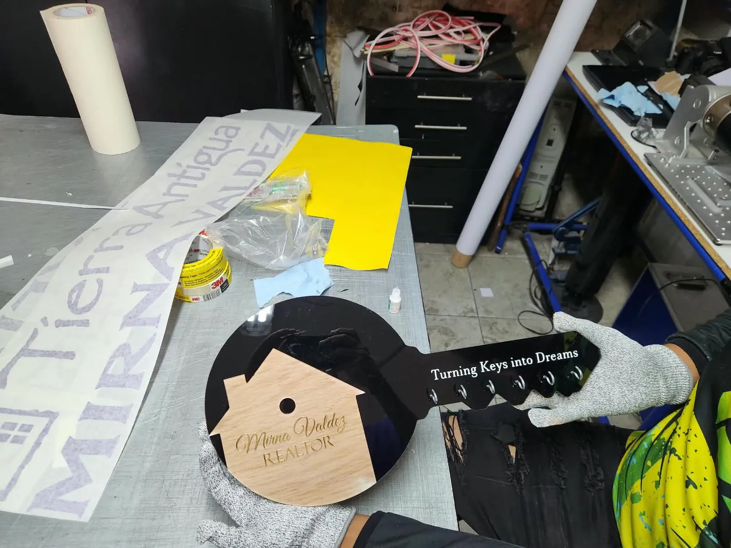 Pieza en forma de llave hecha de acrílico negro y madera grabada con el nombre Mirna Valdez Realtor