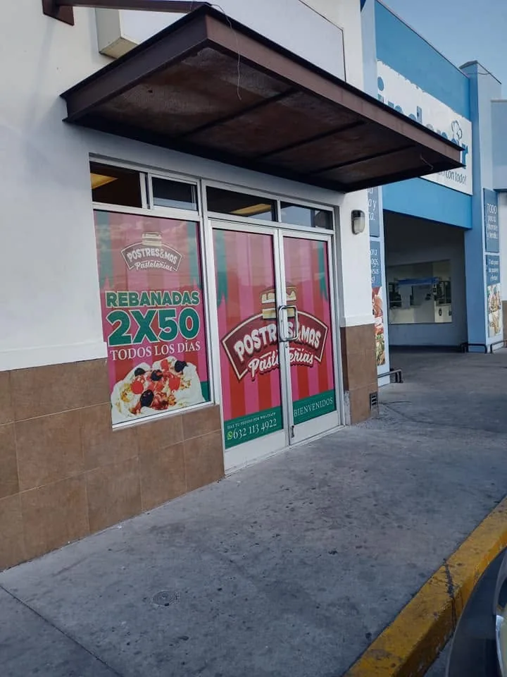 Cristales de una pastelería cubiertos con gráficos rosas de Postres y Más y la promoción 2x50