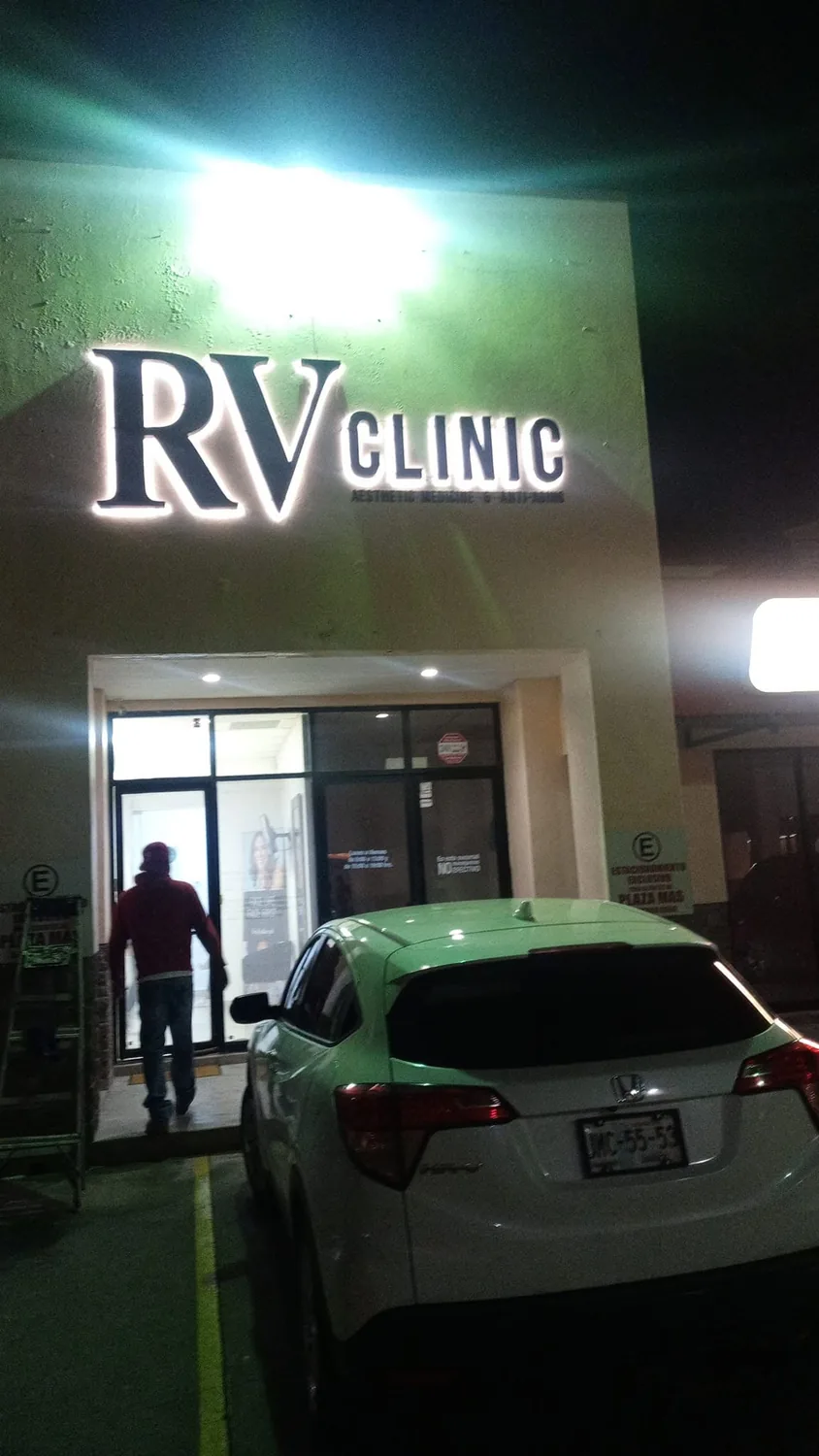 Letras iluminadas de RV Clinic Aesthetic Medicine en la fachada de una clínica de noche
