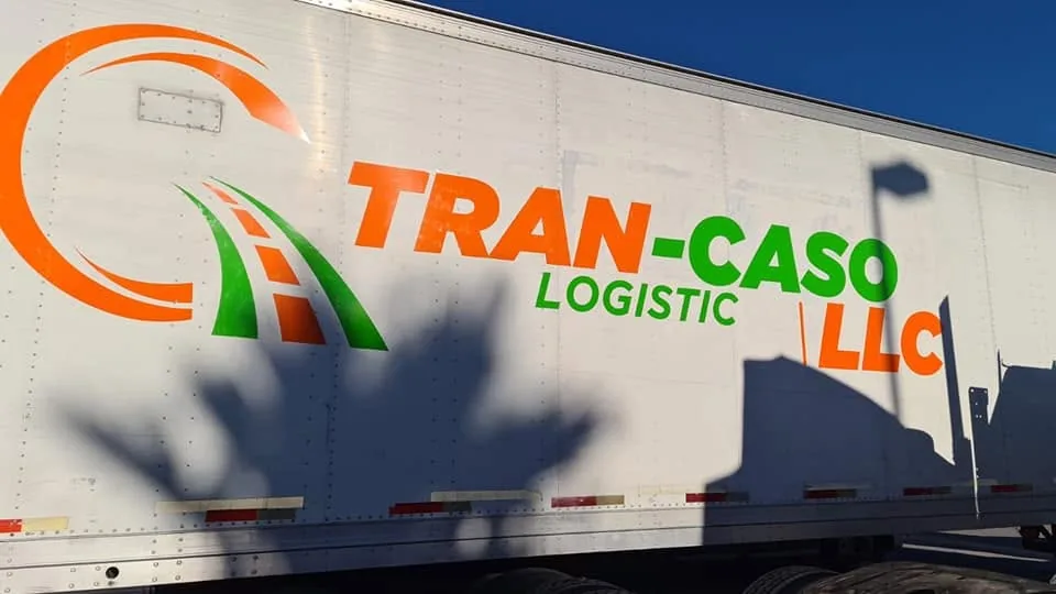 Caja de tráiler blanca con el logotipo de Tran-Caso Logistic en naranja y verde