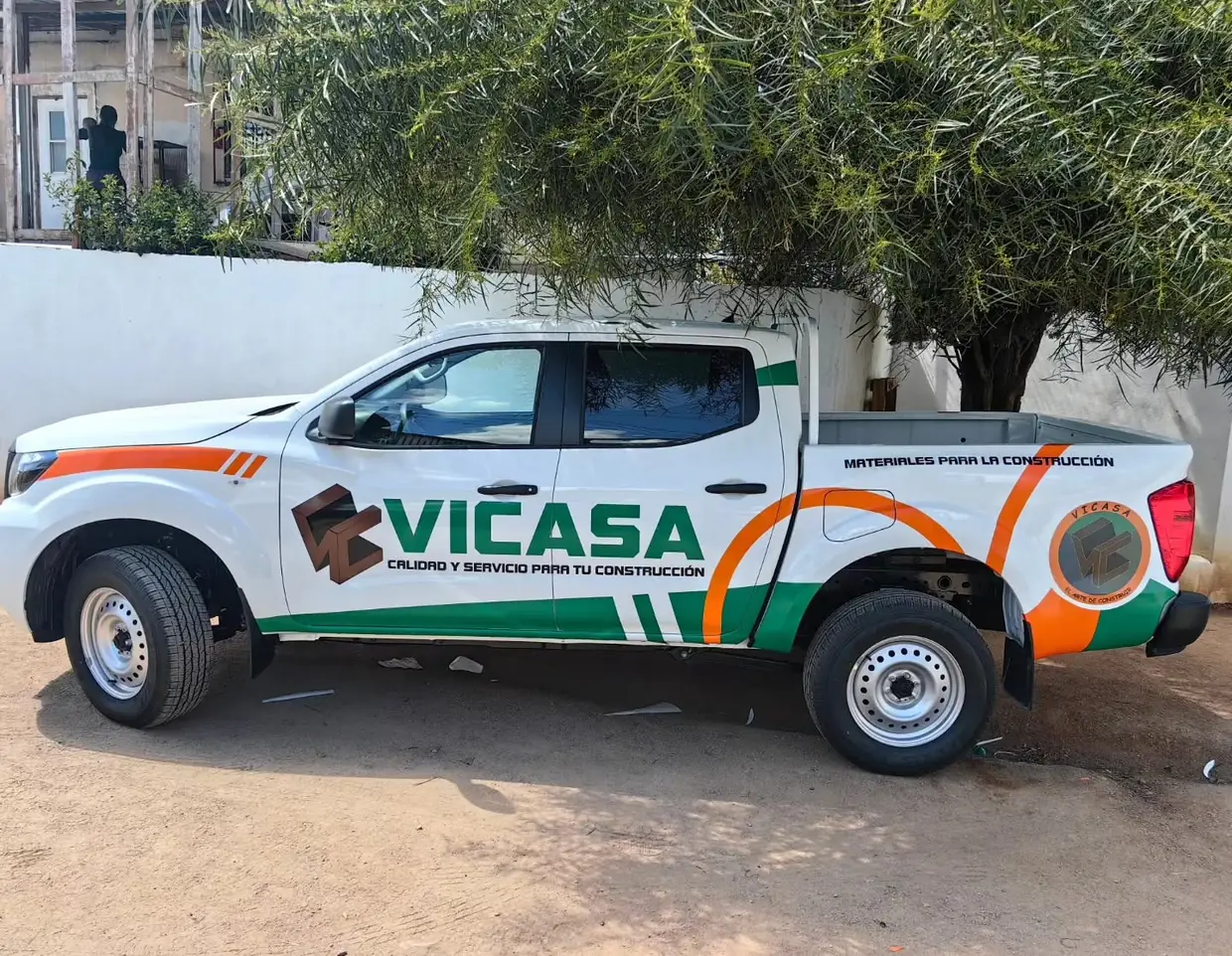 Camioneta pick-up blanca rotulada con el logotipo de VICASA en verde y naranja